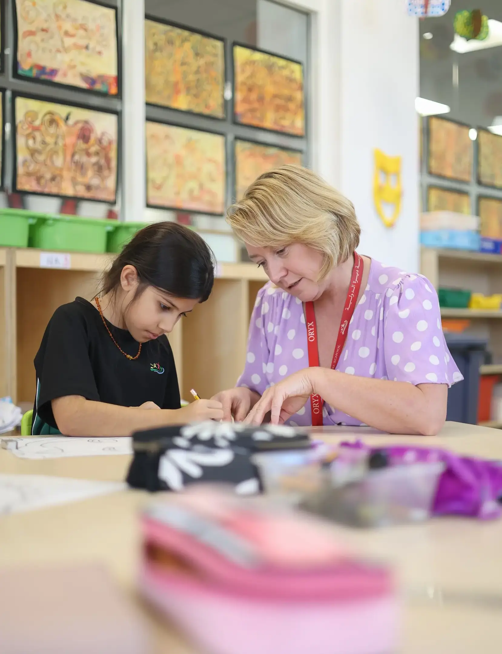 Primary school teacher helping student with class project