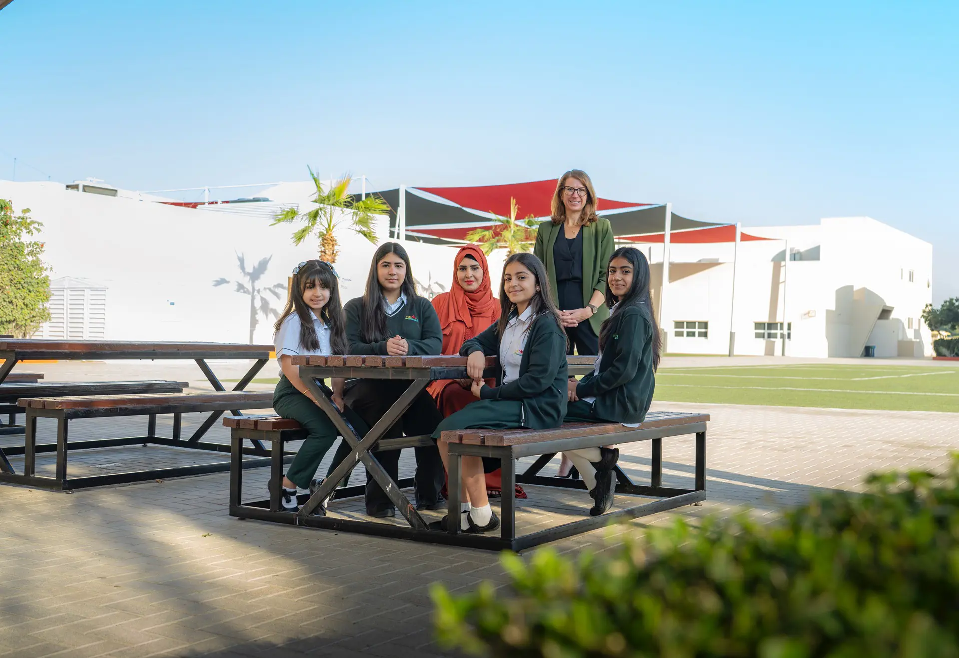 Students from various year groups sat on bench with teachers outside