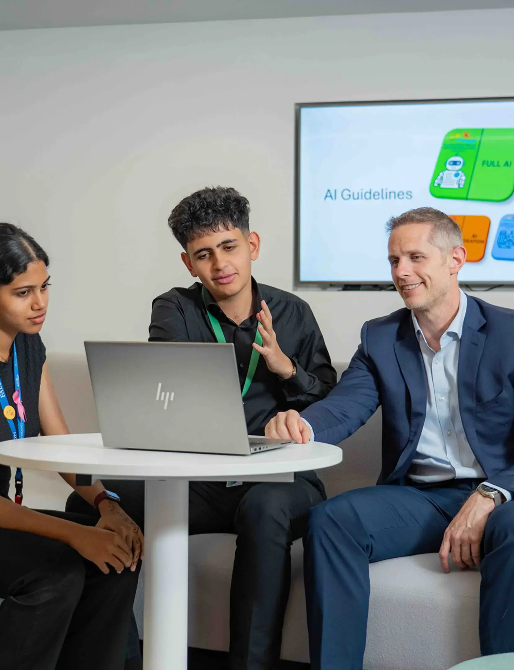 Secondary teacher sat with students looking at laptop